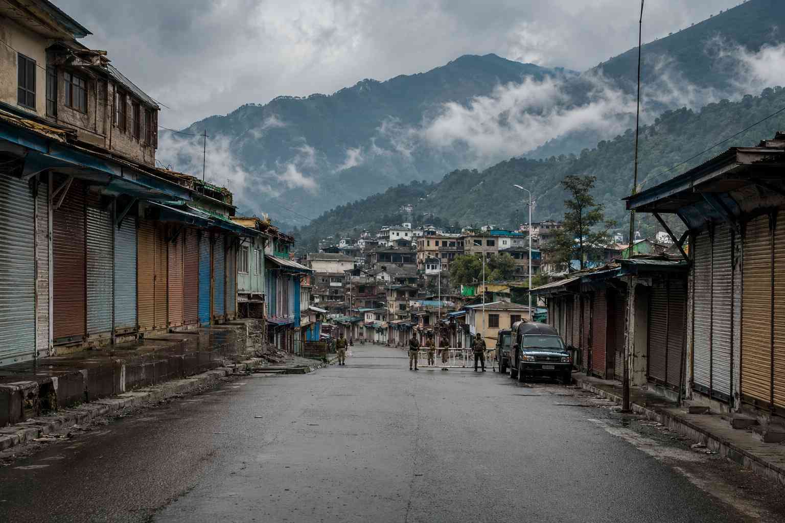 Empty road and closed shops in Muzaffarabad during AJK unrest with mountains in the background